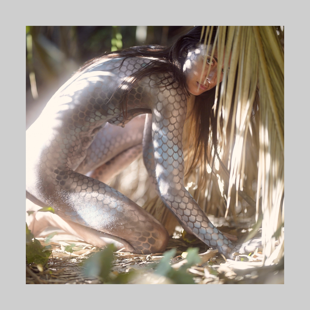 Slither print by Paul Roustan showing a bare figure with reptile-scale body paint in a sunlit outdoor setting.